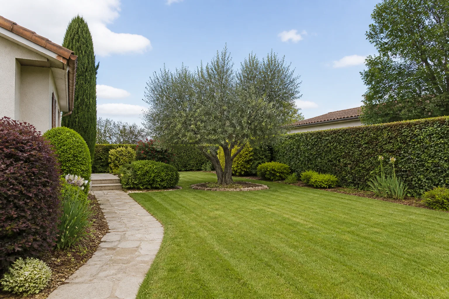 Jardin entretenu avec pelouse tondue et haies taillées à Charlieu